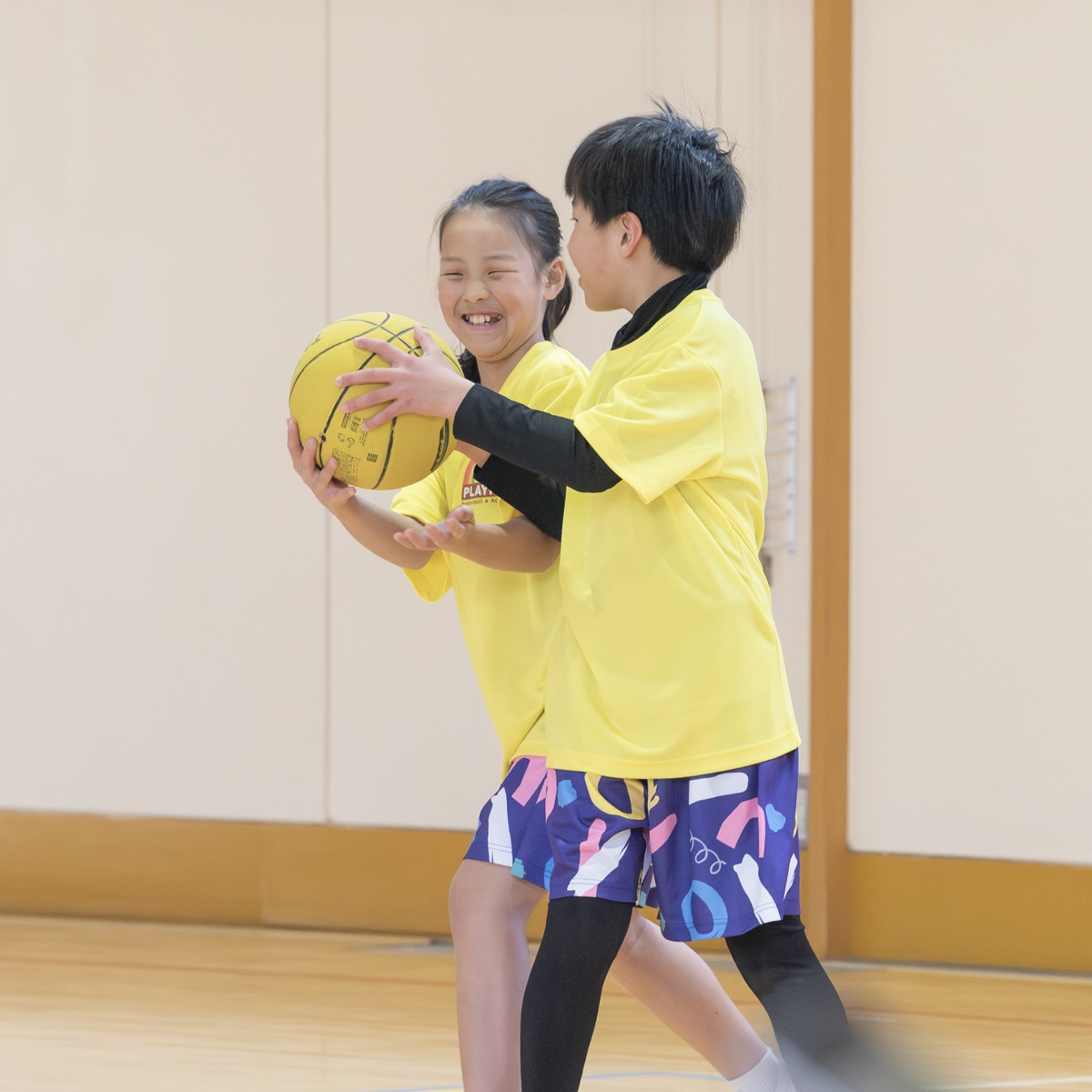 一つのボールに手を伸ばす子ども二人