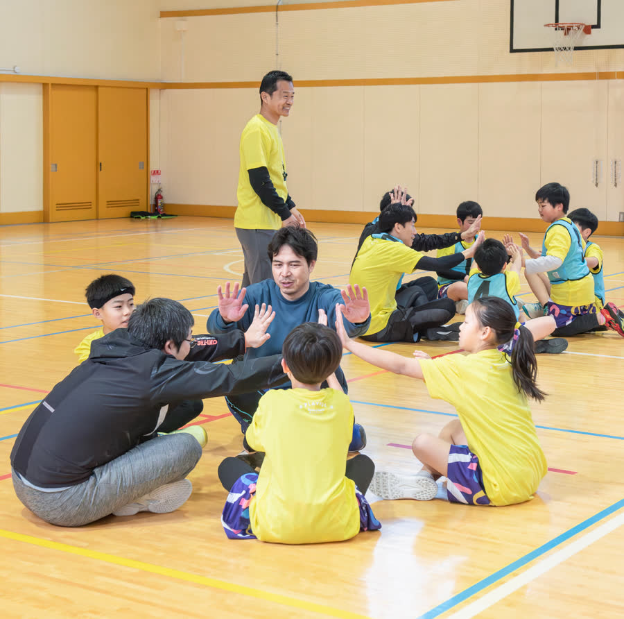 サークルになって手を合わせる子どもたちと大人たち
